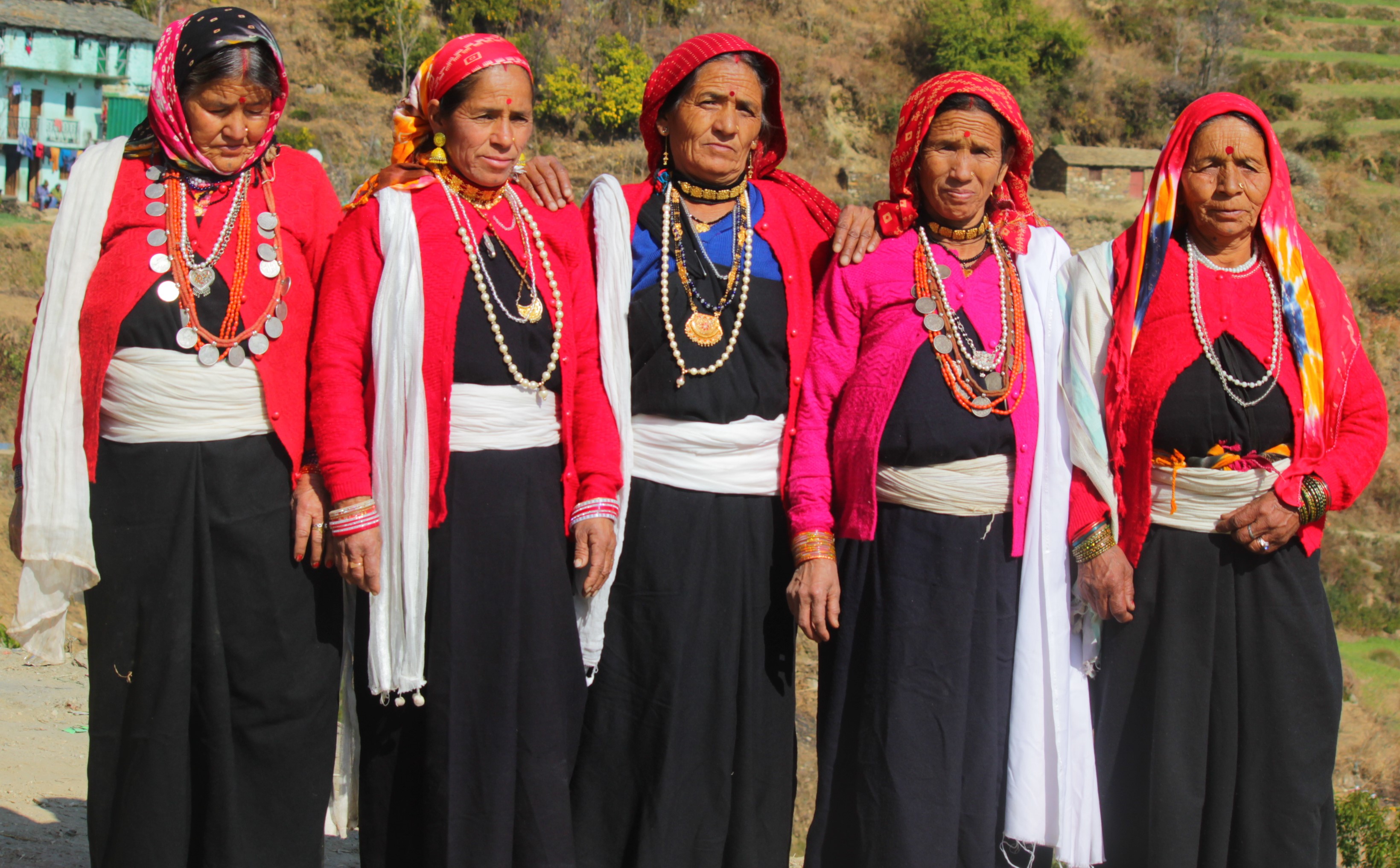 Women in traditional clothing and jewellery pose outdoors at a cultural gathering.